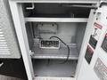 An open compartment of a 2006 Ford F-450 showing a control panel with buttons and a power switch inside a metallic storage area