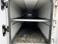 An empty interior view of a 2013 Ford F-650 displaying two metal shelves inside a cargo area