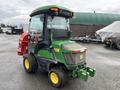 A green and yellow 2014 John Deere 1585 Terrain Cut lawn mower with a glass cabin and a red grass catcher attached to the back