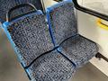 A row of blue and patterned fabric bus seats with a black framework arranged in a forward-facing position