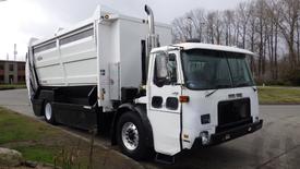 A white 2007 Autocar WXLL garbage truck with a large waste compartment and a visible exhaust pipe on the side