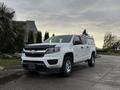 A white 2019 Chevrolet Colorado pickup truck with a black hood and a matching truck cap on the bed