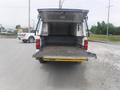 A 2015 Chevrolet Silverado 1500 with its tailgate down revealing an empty truck bed and an open rear cover