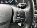 A close-up view of the steering wheel of a 2021 Ford Transit showing control buttons for audio and phone functions