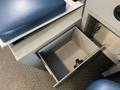 An open storage drawer in the interior of a 2014 Chevrolet Express van with a blue seat cushion above