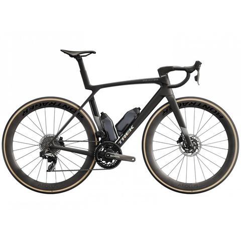 A 2025 Trek Madone SLR 7 Axs Gen 8 road bike featuring a sleek black frame aerodynamic design and disc brakes with large tan tires and a visible battery integrated into the frame