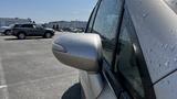 A silver 2006 Honda Fit with a wet side mirror reflecting droplets of water