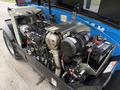 A 2020 Genie GTH-5519 engine compartment featuring a complex arrangement of pipes and components including an air intake system and battery