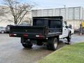 A 2017 Ford F-450 Super Duty truck with a flatbed and dual rear wheels parked with an empty cargo bed