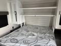 Interior of a 2022 Keystone Hideout RDWE 20RDWE featuring a bed with a patterned mattress positioned against a wall with shelves above