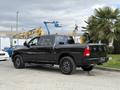 A black 2018 RAM 1500 truck with large tires and an aggressive stance parked on a concrete surface