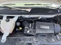 A 2012 Chevrolet Express engine compartment with visible components including the air intake, coolant reservoir, and various hoses and wires