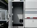 An open storage compartment with hooks and two electrical devices inside on a 2012 Freightliner M2 106 truck