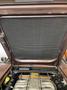 Engine compartment of a 1983 Porsche 928 with a large black mesh cover and visible engine components including silver pipes and a yellow cap