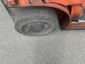 A worn tire of a 2010 Toyota 7FGGU25 forklift with visible tread and metal rim