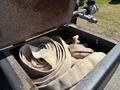 A large brown fire hose coiled inside a rusted metal storage compartment of a 2019 Ford F-750 truck