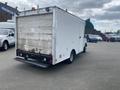 A white 2004 Ford Econoline van with a boxy shape and a rear access door is parked in a lot