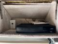 A black receiver nestled inside a fabric-lined compartment with a small white remote and some papers nearby