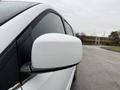 A white 2017 Dodge Grand Caravan with a close-up view of its side mirror covered in water droplets