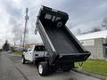 A 2021 Ford F-550 dump truck with its bed raised is positioned on a street showcasing its truck bed and wheels