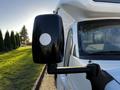 A side mirror of a 2017 Chevrolet Express with a black casing and a circular white reflector on the front