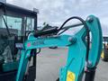 A 2024 AGT Industrial QH13R Mini Excavator with a teal arm and hydraulic hose is prominently featured in the foreground