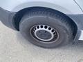 A close-up view of a tire on a 2022 Mercedes-Benz Sprinter showcasing a metal rim with circular holes and a rugged tire tread design