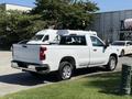 A white 2021 Chevrolet Silverado 1500 pickup truck is parked with its bed and rear visible showcasing a modern design and chrome accents