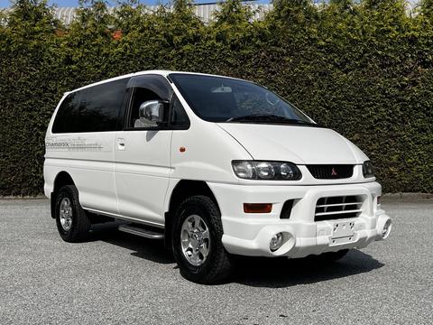 A white 2003 Mitsubishi 7 Passenger Van with a sporty design featuring a prominent front grill and alloy wheels