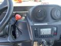The interior control panel of a 2014 Kubota X1100C featuring a gear lever with a red handle an instrument display and various control buttons