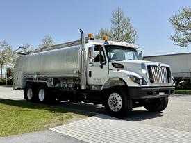 A 2009 International 7500 truck with a silver tank body and black wheels parked on a driveway