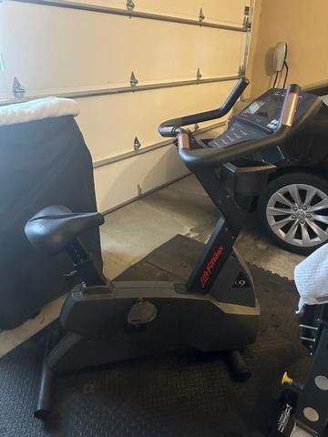 A black Lifecycle stationary bike with a sleek design featuring a digital display handlebars and a comfortable seat positioned for indoor cycling