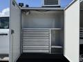 An open storage compartment of a 2023 Ford F-550 showcasing multiple drawers and shelves for organization