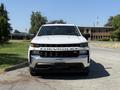 A white 2021 Chevrolet Silverado 1500 pickup truck is parked with its front facing the viewer showcasing its bold grille and headlights