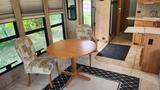 A dining area in a 2007 Winnebago Adventure featuring a round wooden table and two patterned chairs with a rug underneath