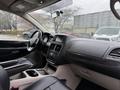 Interior of a 2017 Dodge Grand Caravan featuring black leather seats a dashboard with climate controls and a center console with storage compartments