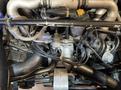 Engine compartment of a 1983 Porsche 928 featuring various metal and rubber components including hoses cables and connection points