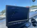 A dashboard monitor displaying a reversing camera view with guidelines for parking assistance