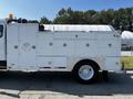 A 2004 Freightliner M2 vehicle with a white service body featuring multiple compartments and a diamond plate tool box on the side