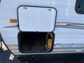 A 2016 Jayco 265RLSW travel trailer showing an access panel open revealing storage space with some equipment inside