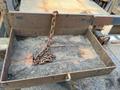 A rusty metal tray with a chain lying inside it and covered in dirt and debris