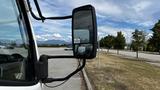 A 2018 Mitsubishi Fuso FE truck with a side mirror reflecting the landscape and parked vehicles