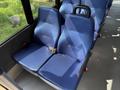 Two blue upholstered seats with safety belts inside a vehicle interior