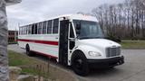 A 2013 Freightliner M2 106 bus painted white with red stripes and a large side door open for entry