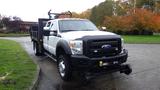 A 2011 Ford F-550 truck with a flatbed and a black grille prominently displayed in the foreground