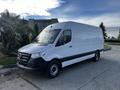 A 2022 Mercedes-Benz Sprinter van with a white exterior and black trim parked beside a palm tree