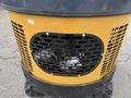 A yellow industrial mini excavator with a black perforated grille and visible engine components in the front section