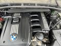 A 2011 BMW 3-Series engine view featuring the BMW logo and a sleek black engine cover with silver stripes and various mechanical components visible
