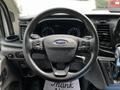 Steering wheel of a 2022 Ford Transit featuring the Ford logo and control buttons on the left side with a gear shift lever visible in the foreground