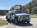 A 2016 Ford F-550 bucket truck with a white body and amber lights on top, parked with a utility box in the back and an extended boom for reaching high areas